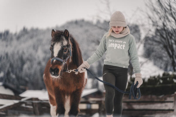 Kind mit Pony im Schnee